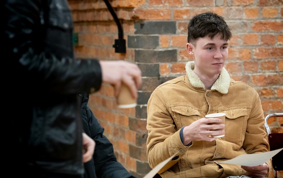 James, a student, sits with a cup of coffee before participating in a group discussion