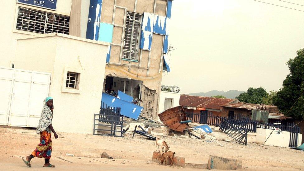 A woman walks by the damaged Michika Local Government secretariat in Michika, a city recaptured from Boko Haram by the Nigeria military early this year, on May 10, 2015.