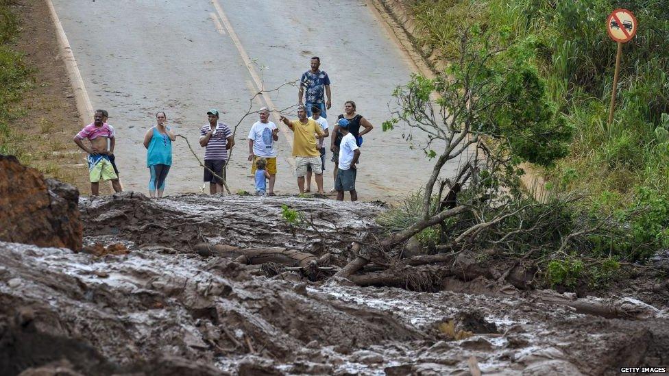 Local people gather next to the mud