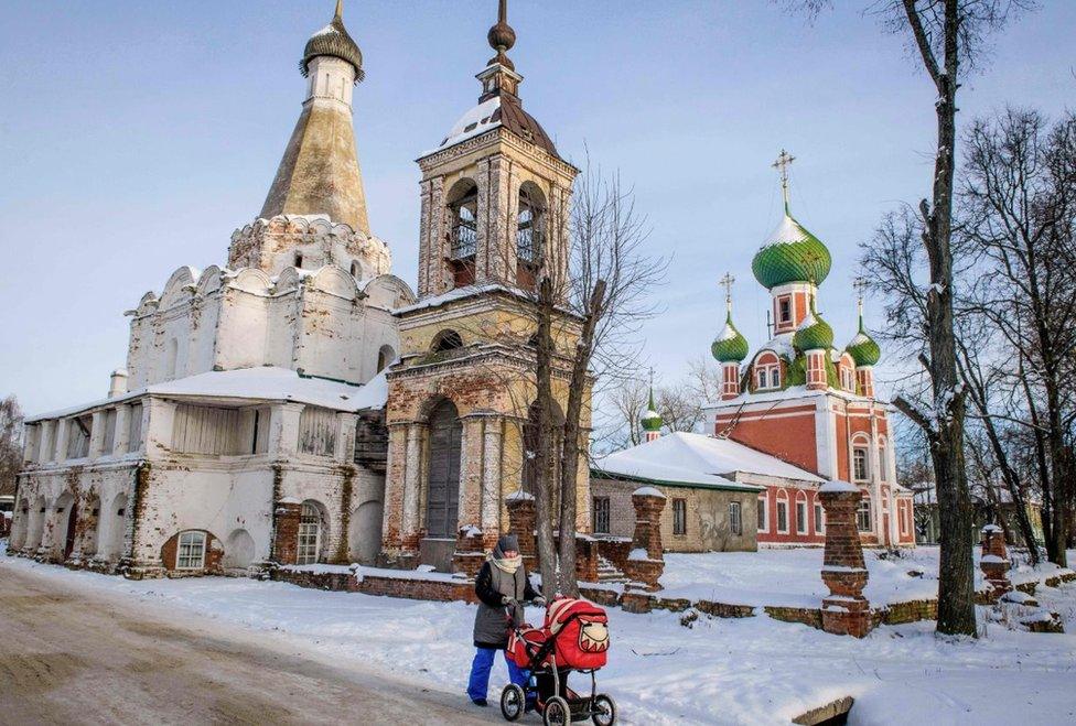 A woman pushes a pram in front of several Orthodox churches in the historical centre of the town of Pereslavl-Zalessky on January 25, 2018