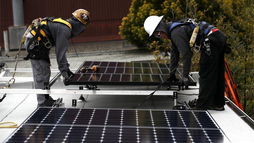 Solar panel installers work on a roof in San Francisco, California