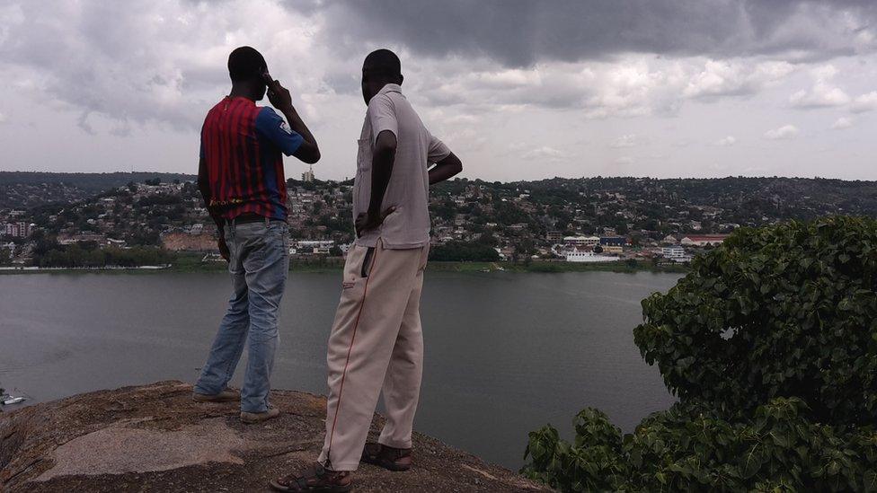 Two people looking over Mwanza, Tanzania one on the phone