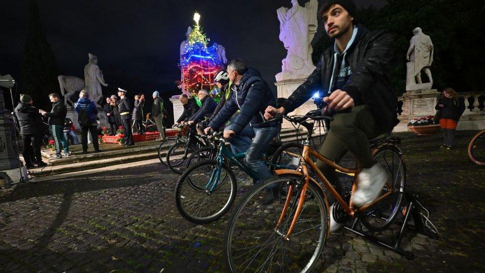 people cycling with christmas tree in the background