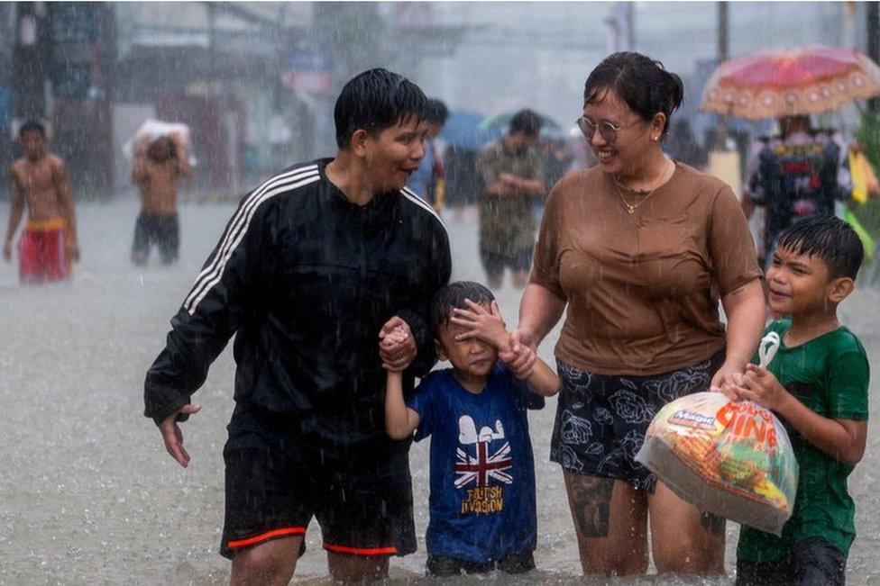 People wade through a flooded road, due to monsoon rains and typhoon Doksuri, in Balagtas, Bulacan province, Philippines, July 29, 2023