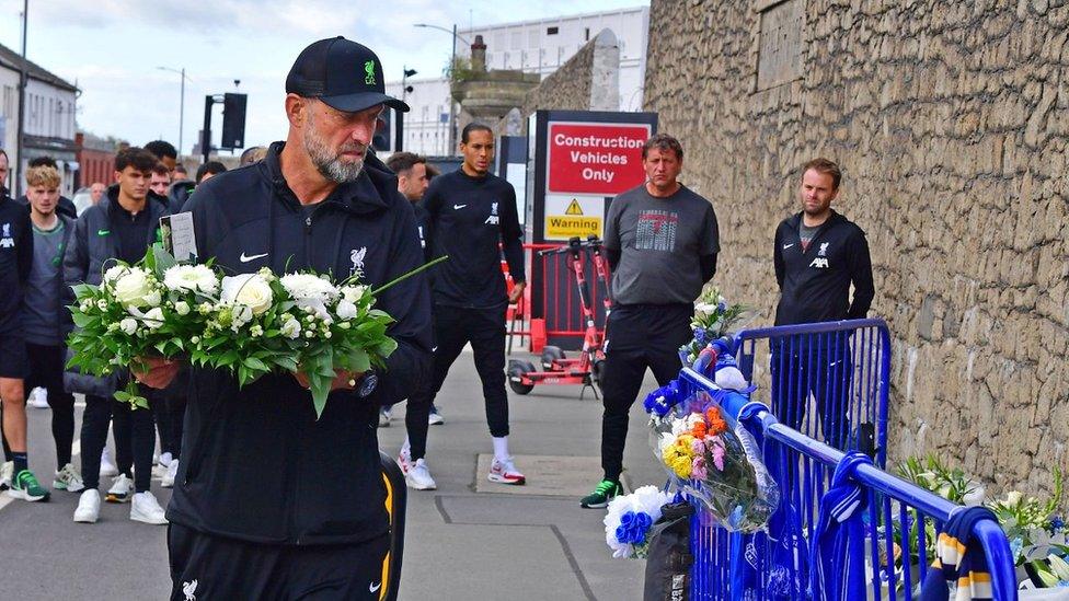 Jurgen Klopp carries flowers with squad behind