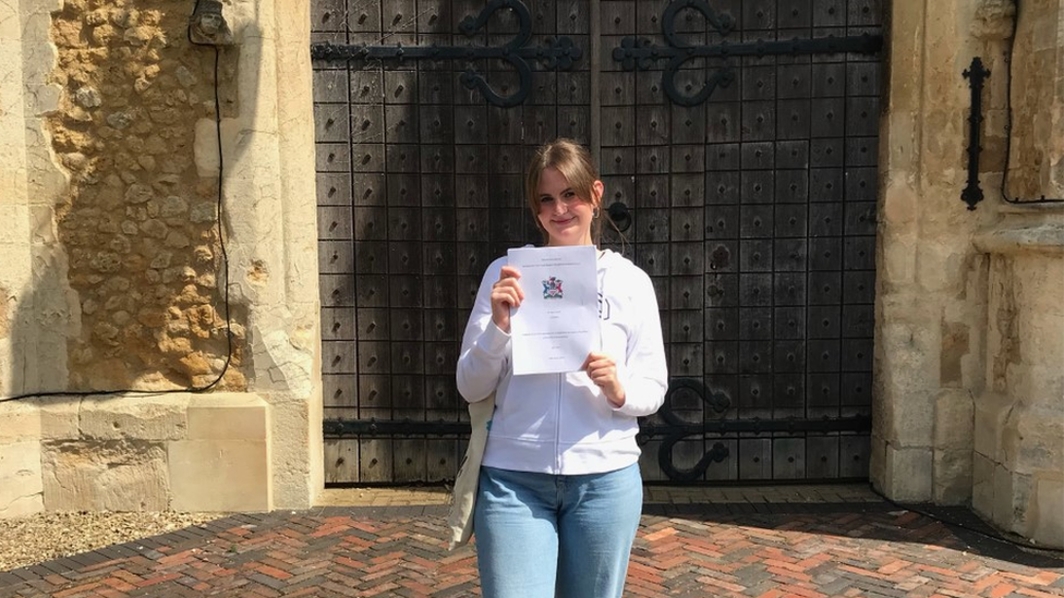 Jess Herbert holding up her dissertation