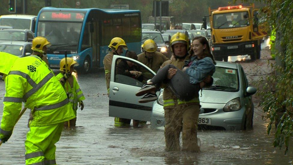 Firefighters helping motorist from vehicle during flood