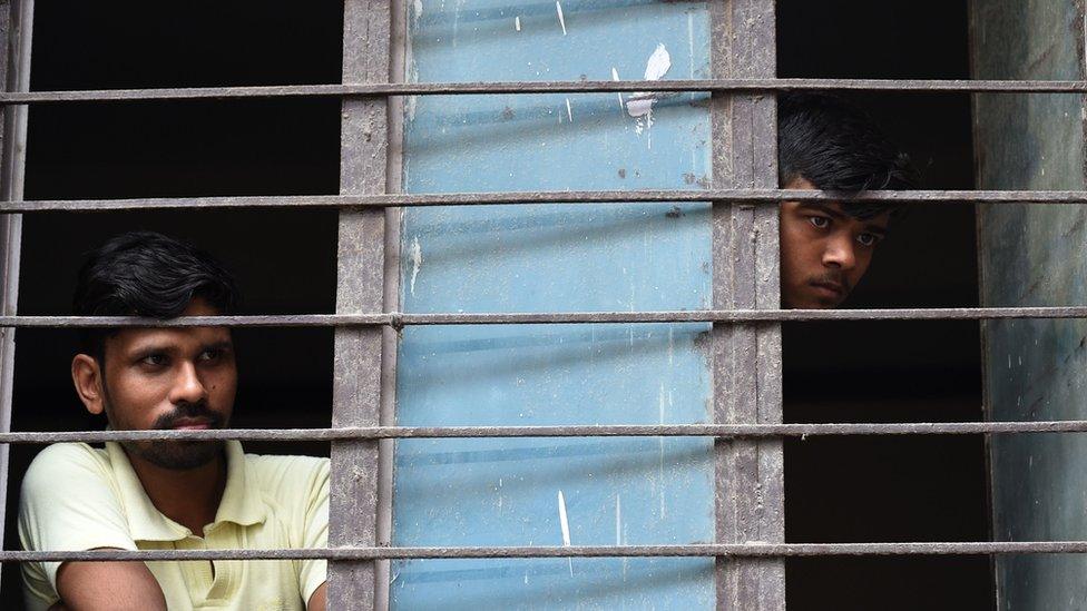 Neighbours look out from a window near the building where 11 family members were found dead inside their home in the neighbourhood of Burari in New Delhi on July 1, 2018