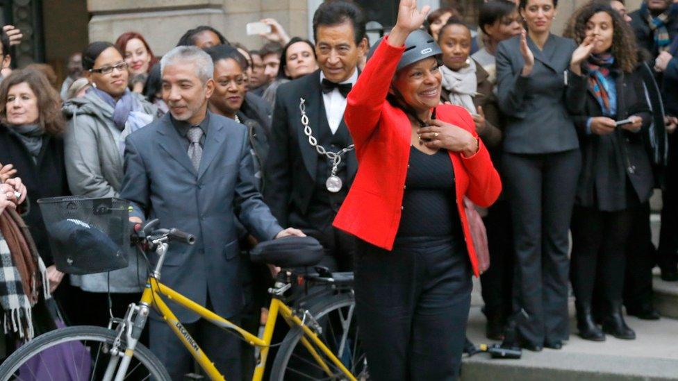 Outgoing Justice Minister Christiane Taubira waves as she prepares to leave the French Justice Ministry on a bike in Paris on 27 January 2016, after she resigned over the president's push to revoke citizenship of convicted terrorists with dual nationality