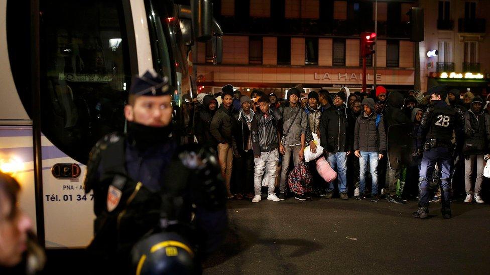 Migrants wait before entering buses