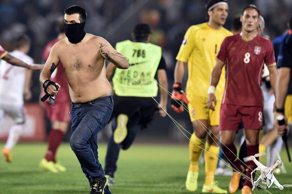 A masked Serbian supporter grabbed the drone as clashes broke out in Belgrade (14 Oct)