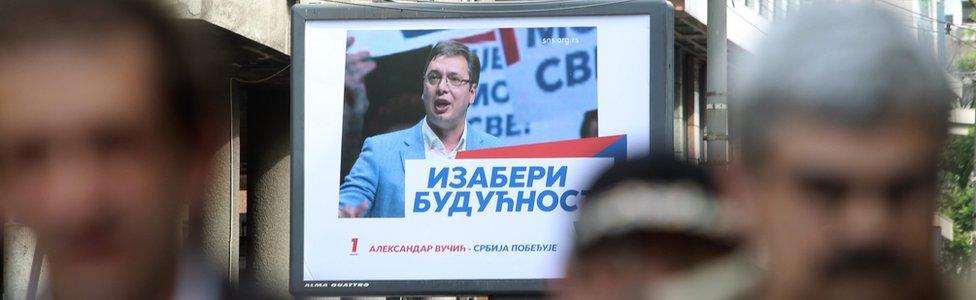 People walk past an election poster of poster of Prime Minister of Serbia and Serbian Progressive Party (SNS) leader Aleksandar Vucic in Belgrade