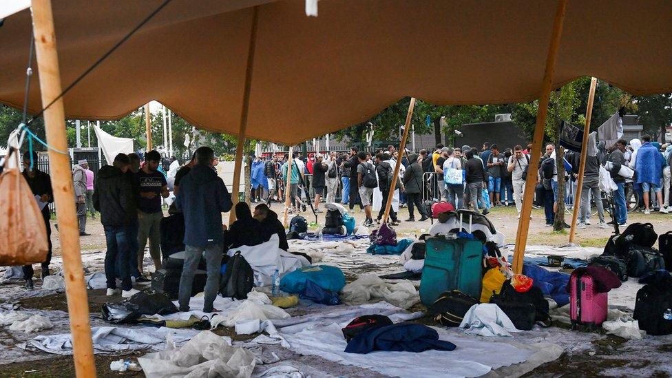 People wait outdoors on the damp ground at the Ter Apel reception centre for asylum seekers. Photo: August 2022