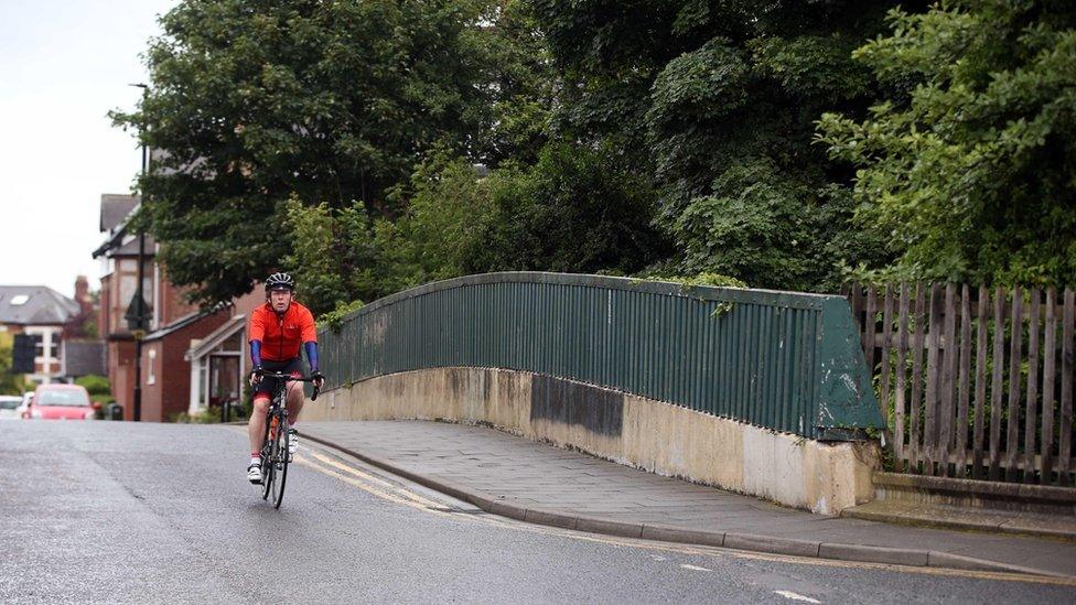 A cyclist rides over Stoneyhurst Bridge