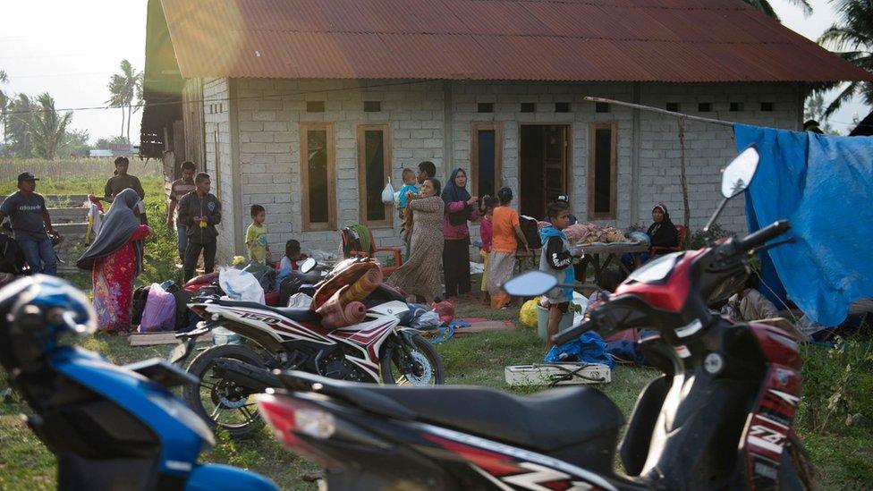 Residents stand outside a house as they are afraid to stay indoors in their homes in Palu in Central Sulawesi on September 29, 2018