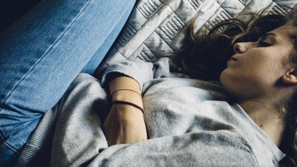 A stock image of a woman lying on a bed