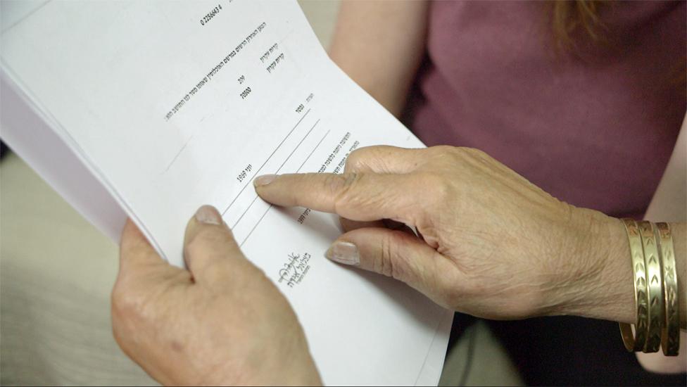 Leah shows a death certificate for her daughter from 1969