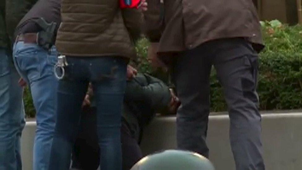 Belgian police detaining a suspect during a raid in the Molenbeek quarter of Brussels