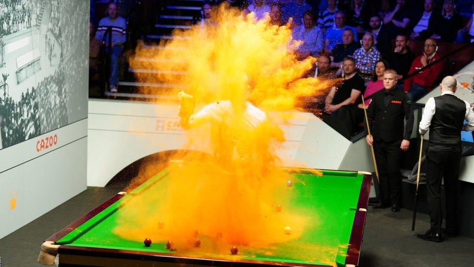 A protestor throws sand in the air while sat on table one at the snooker World Championship