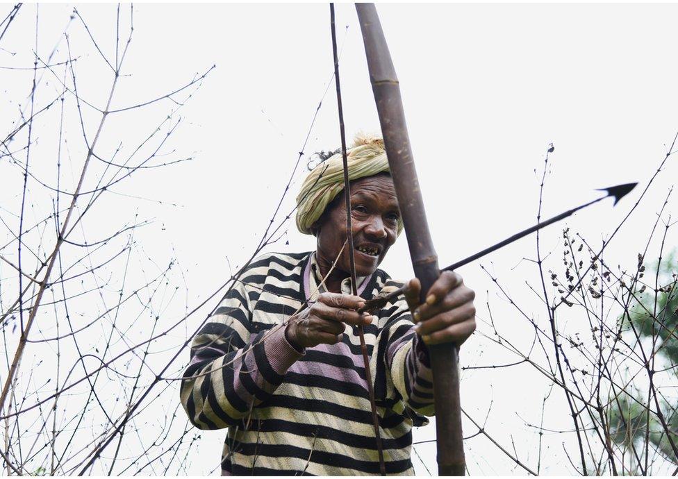 A man uses his bow and arrow to hunt wild animals.