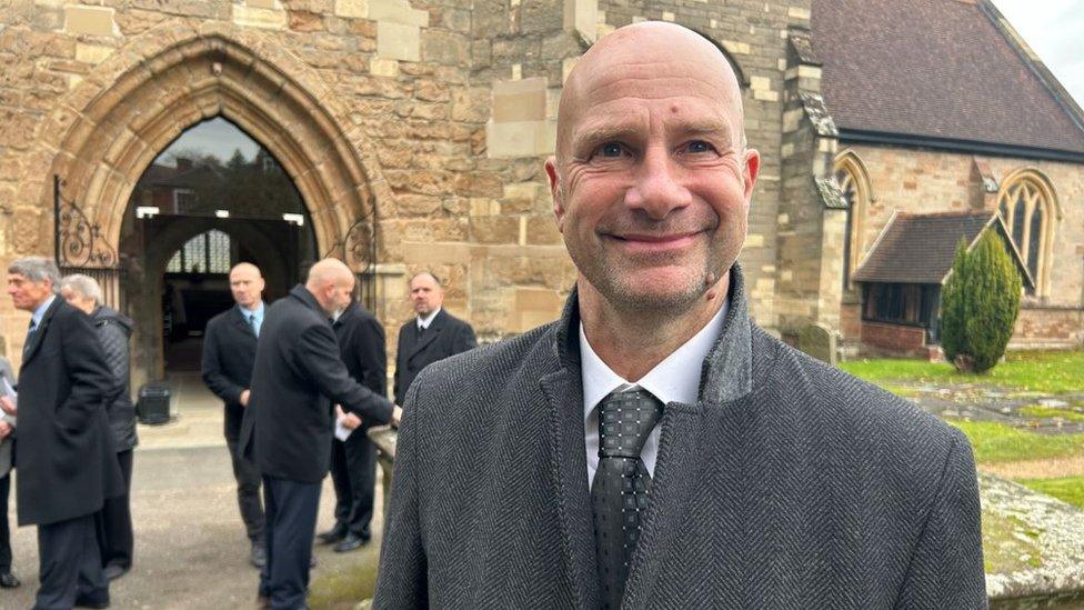 Clifford Freeman standing outside St Mary's Church in a suit