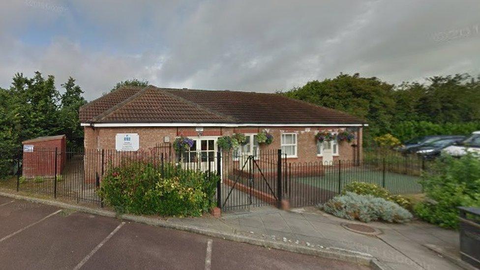 Single-storey brick-built community centre with bushes around the entrance