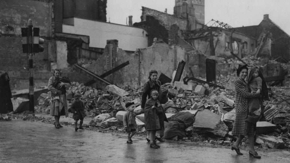 People walk past a devastated buildings after a German bombing raid on Plymouth in 1941