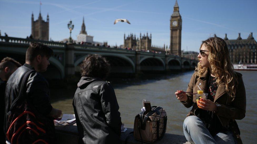 People sitting opposite the Houses of Parliament