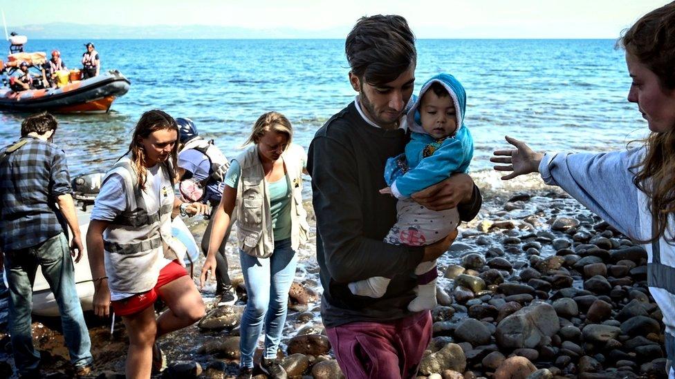 Migrants are helped by rescuers as they arrive on the Greek island of Lesbos after crossing the Aegean Sea from Turkey, 16 September 2019