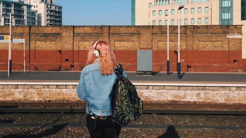 A woman waits at a train platform