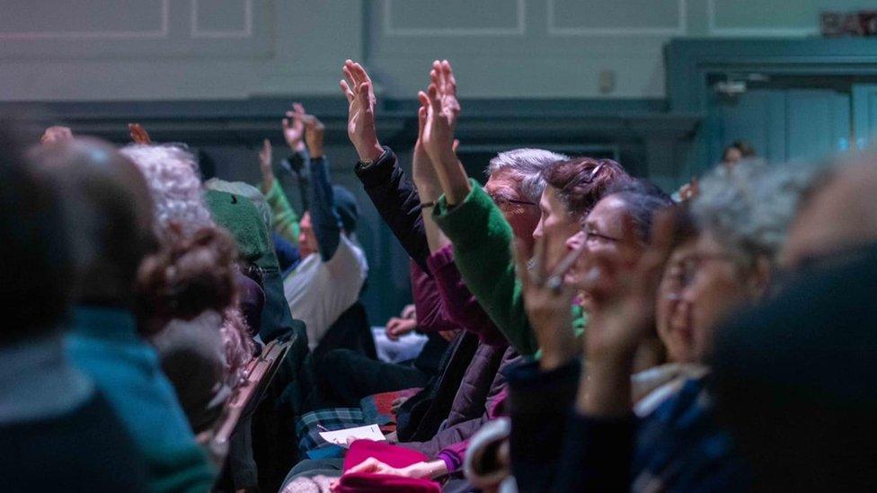 A close up of the audience, some with raised hands