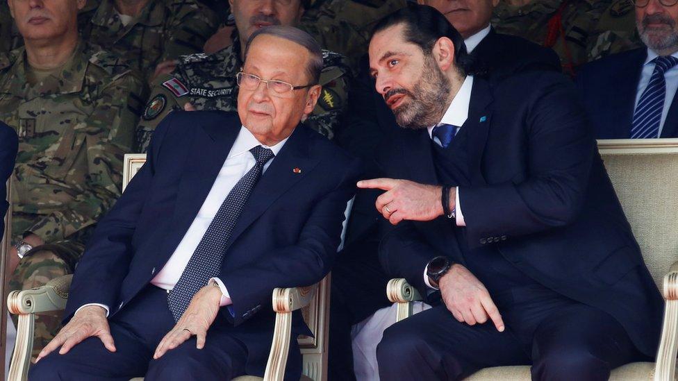 Lebanese President Michel Aoun (L) speaks to caretaker Prime Minister Saad Hariri (R) at a military parade on 22 November 2019