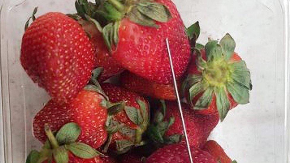 A needle next to strawberries