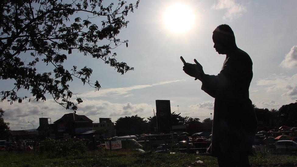 Eric Kasinga in silhouette on his mobile phone in DR Congon