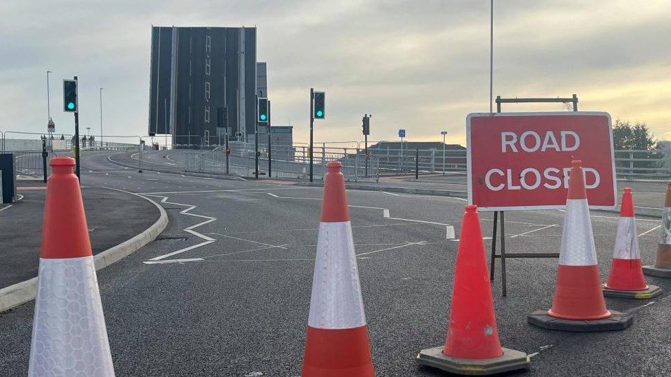 Road closure signs and cones with the Herring Bridge in the raised position in the background