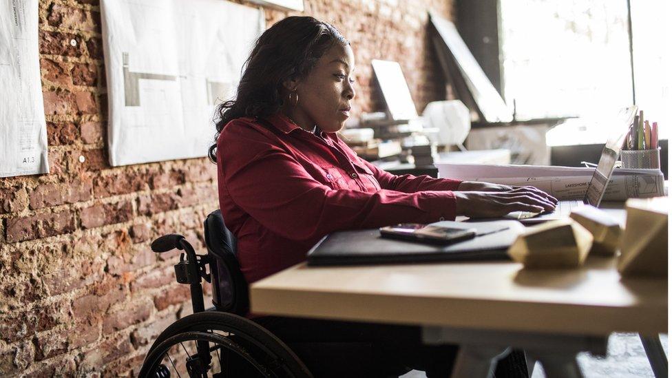 Woman in a wheelchair working at a desk on a laptop