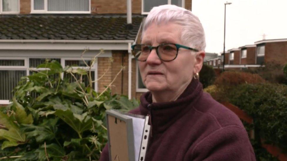 An elderly resident outside her home