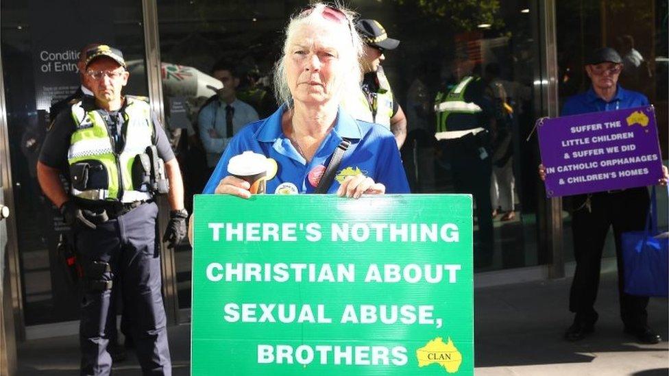 A protester outside a court hearing for Pell holds a sign saying: "There's nothing Christian about sexual abuse, brothers."