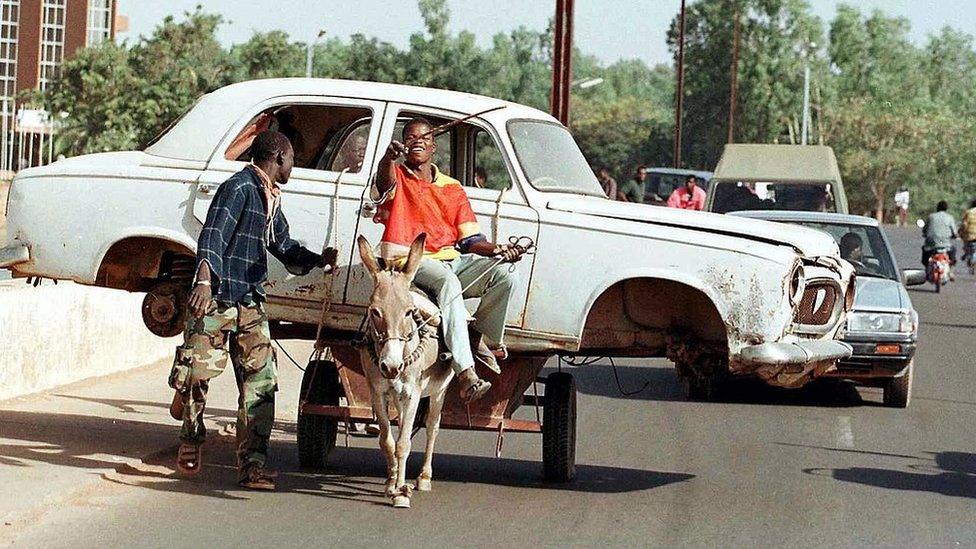 Already busy with thousands of mopeds, the traffic is held up at a crossroads in Ouagadougou, by a donkey cart carrying a car (archive shot)