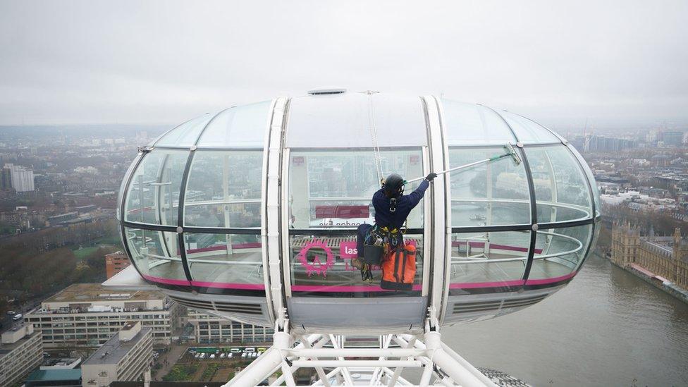 A window cleaner scrubs the London Eye pods