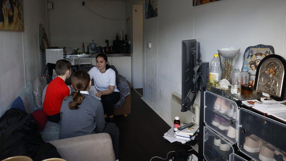 Paula Aleksandros with her two children in their shipping container