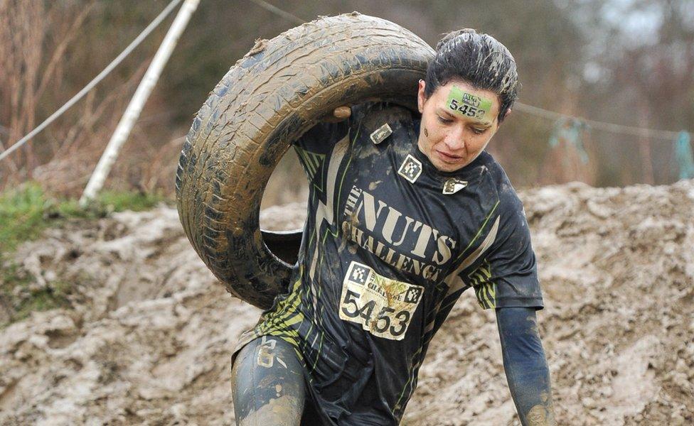 Woman carrying a tyre during a mud run