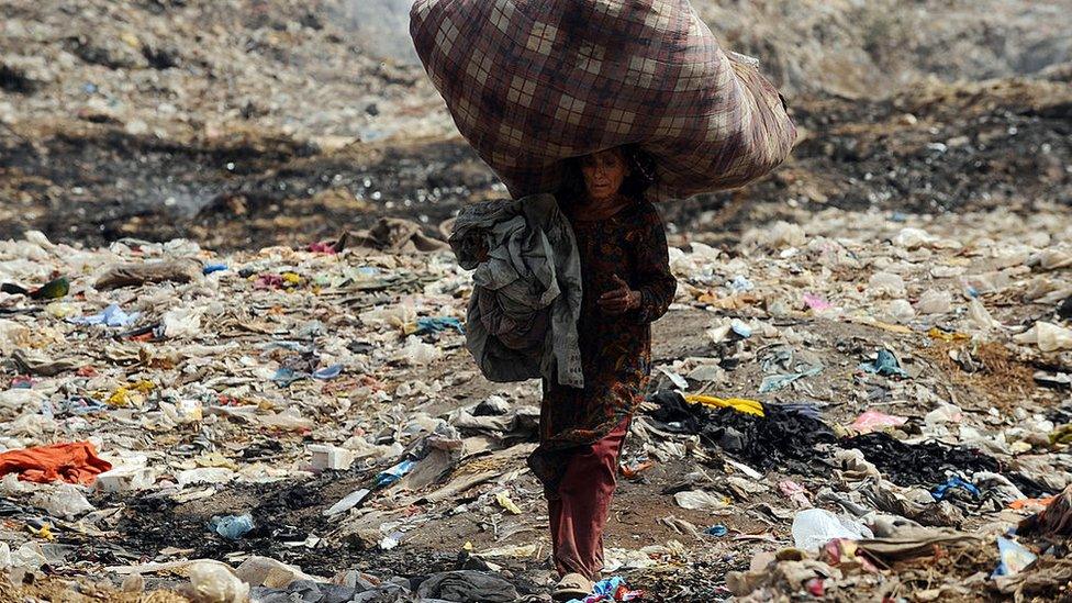 A Pakistani woman carries used clothing over her head