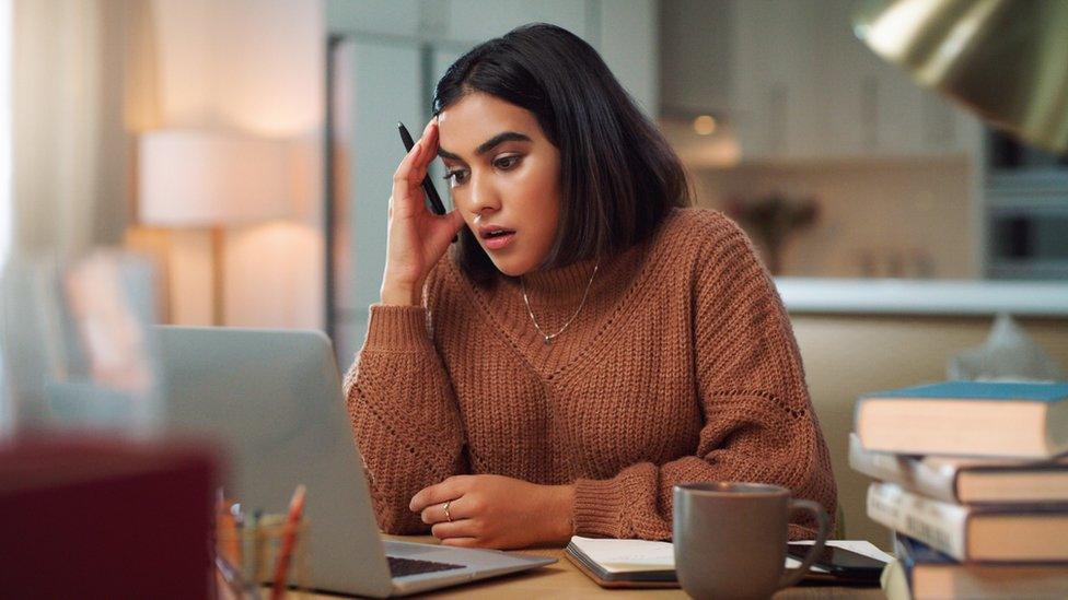 A student with her head in her hand in front of a laptop