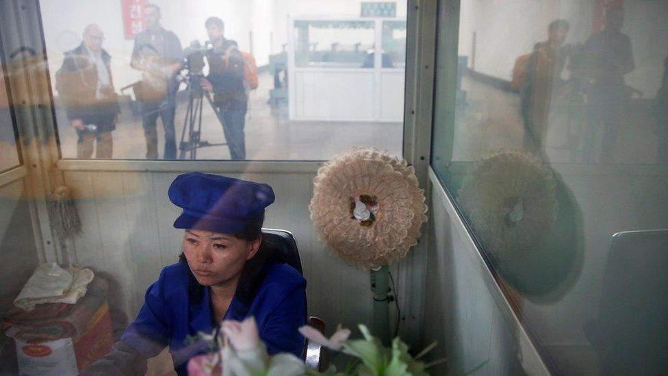 A North Korean worker sits in a booth at a wire factory