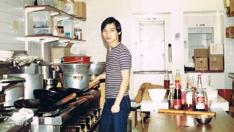 Angela's dad in the kitchen with a wok in his hand