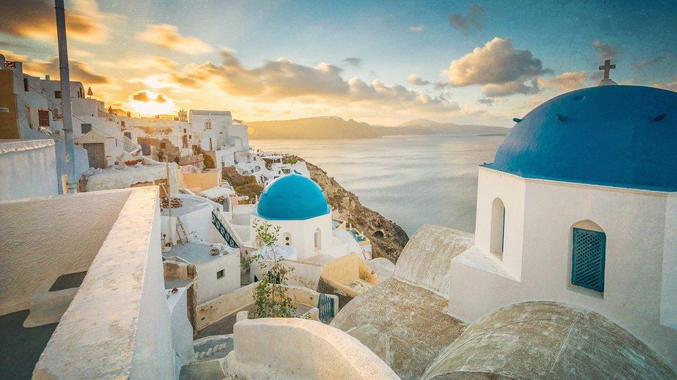 Church And Houses In Town By Sea At Santorini During Sunrise - stock photo