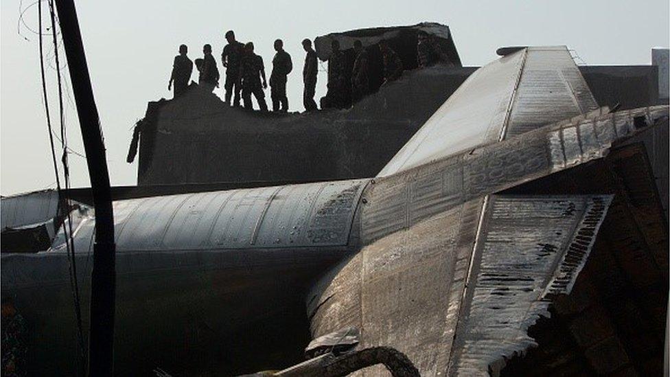 Military personnel and search and rescue teams comb through the wreckage of a military transport plane which crashed into a building on June 30, 2015 in Medan