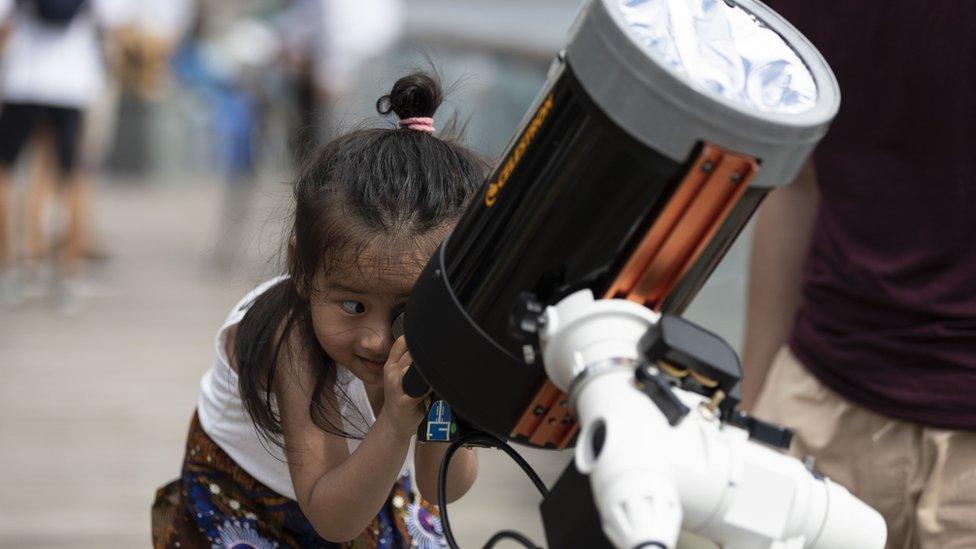 girl-looking-through-protective-solar-eclipse-telescope