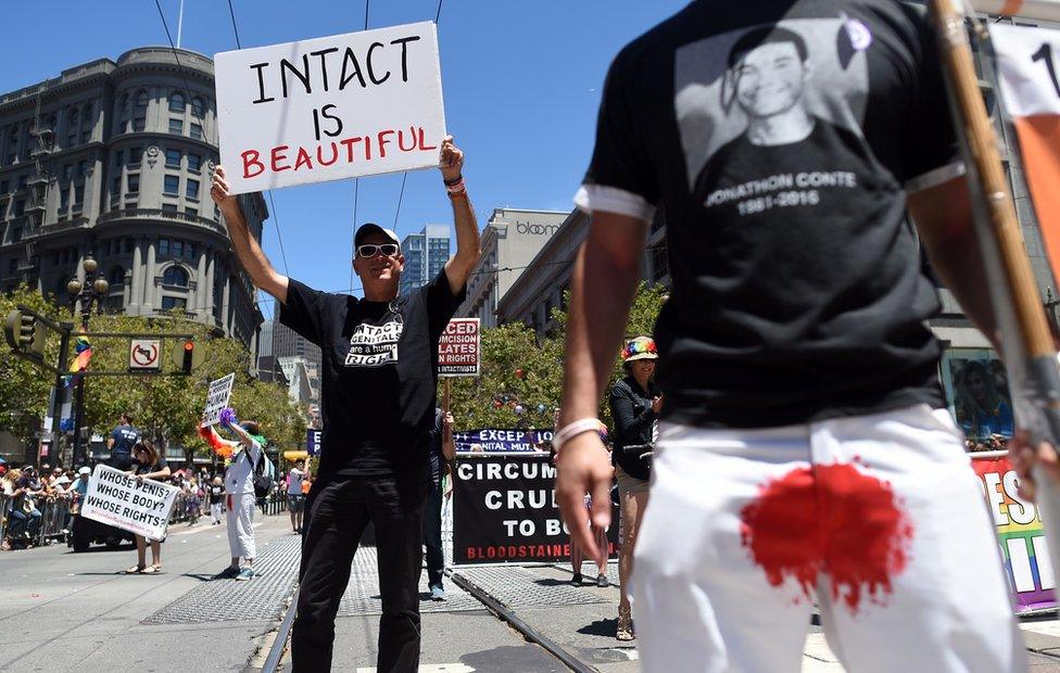 Jason Fairfield (L) holds up an anti-circumcision sign while marching with the Bay Area Intactivists along the Gay Pride parade route in San Francisco, California on Sunday, June, 26, 2016